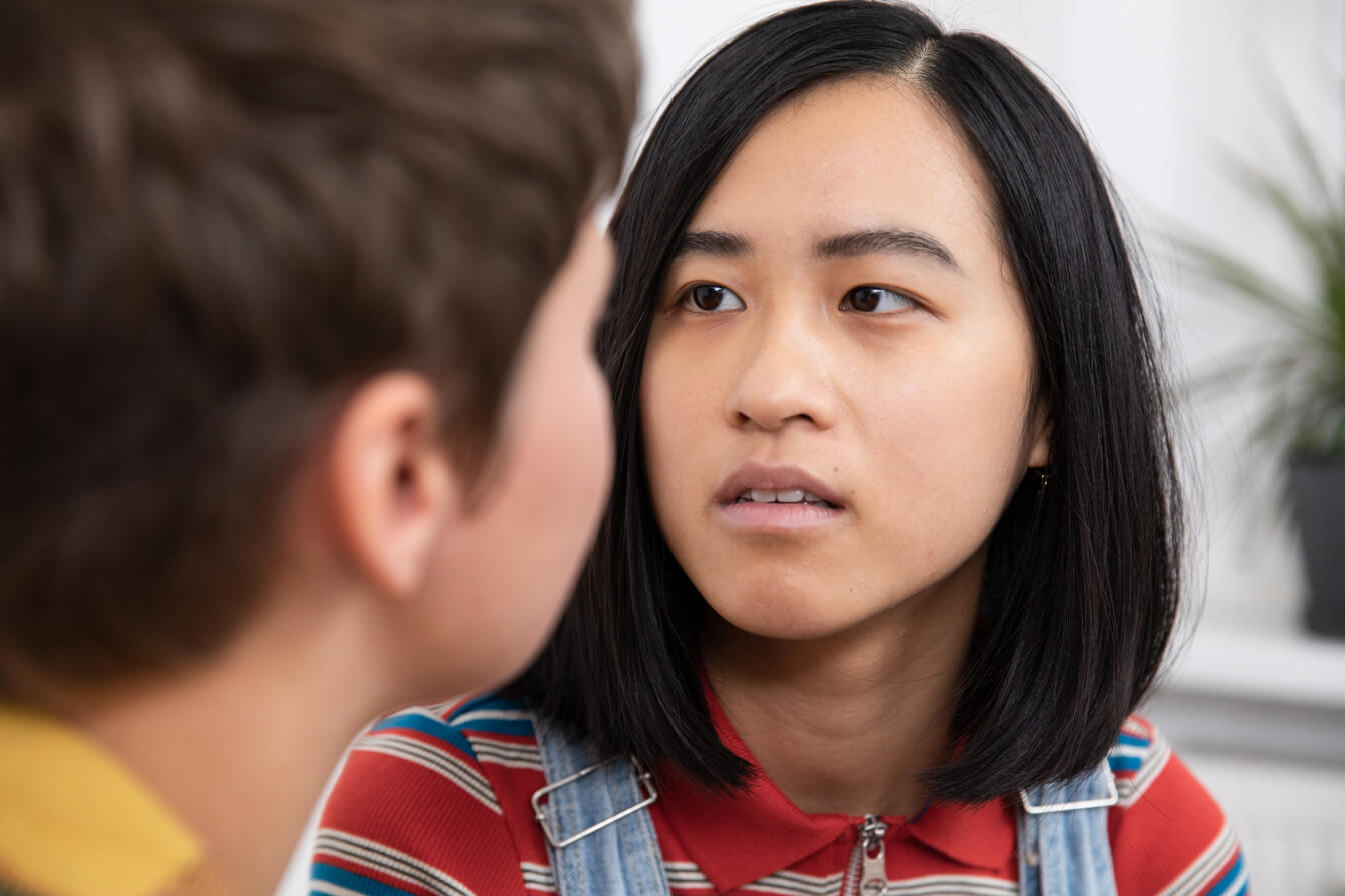 Eine junge Frau schaut fragend zu einer anderen Person.