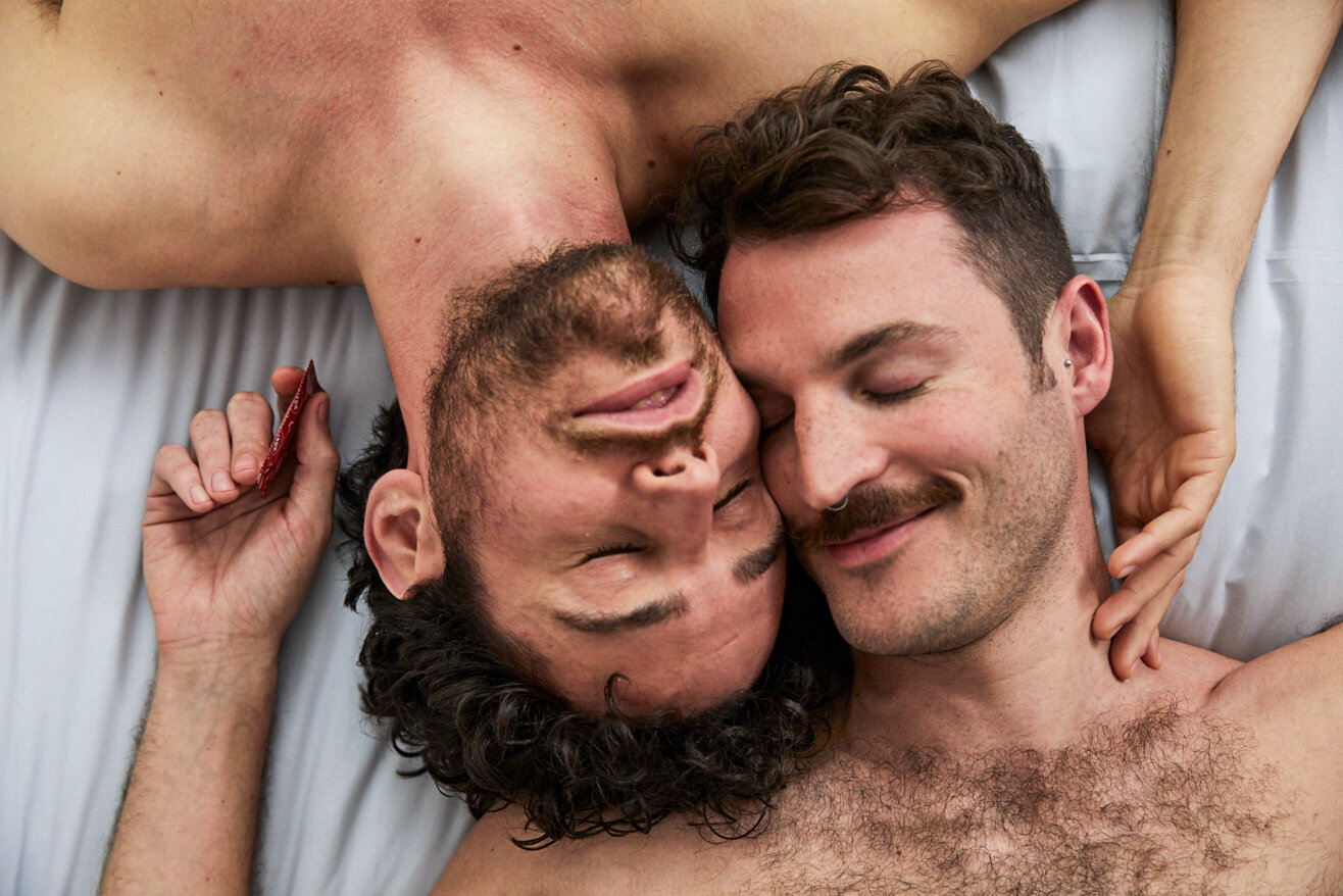 Zwei Männer liegen mit den Köpfen nebeneinander in einem Bett.