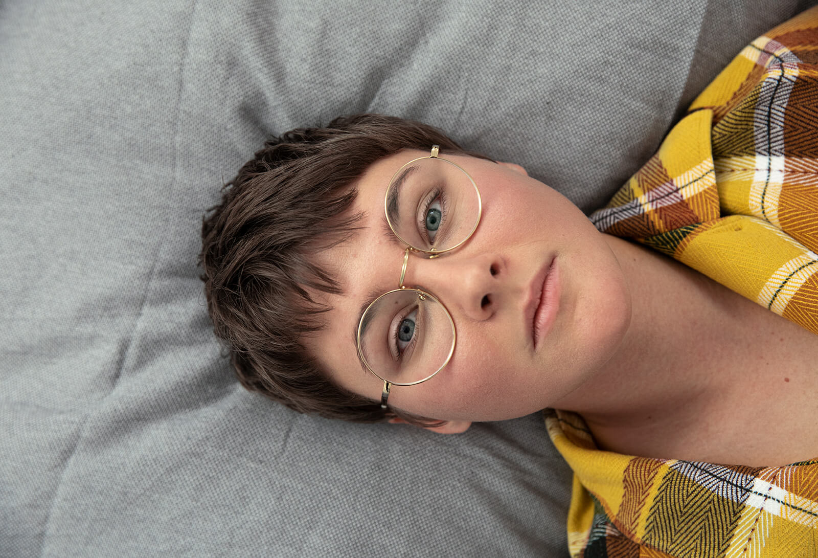 Eine Person liegt auf ihrem Bett und blickt nachdenklich nach oben.