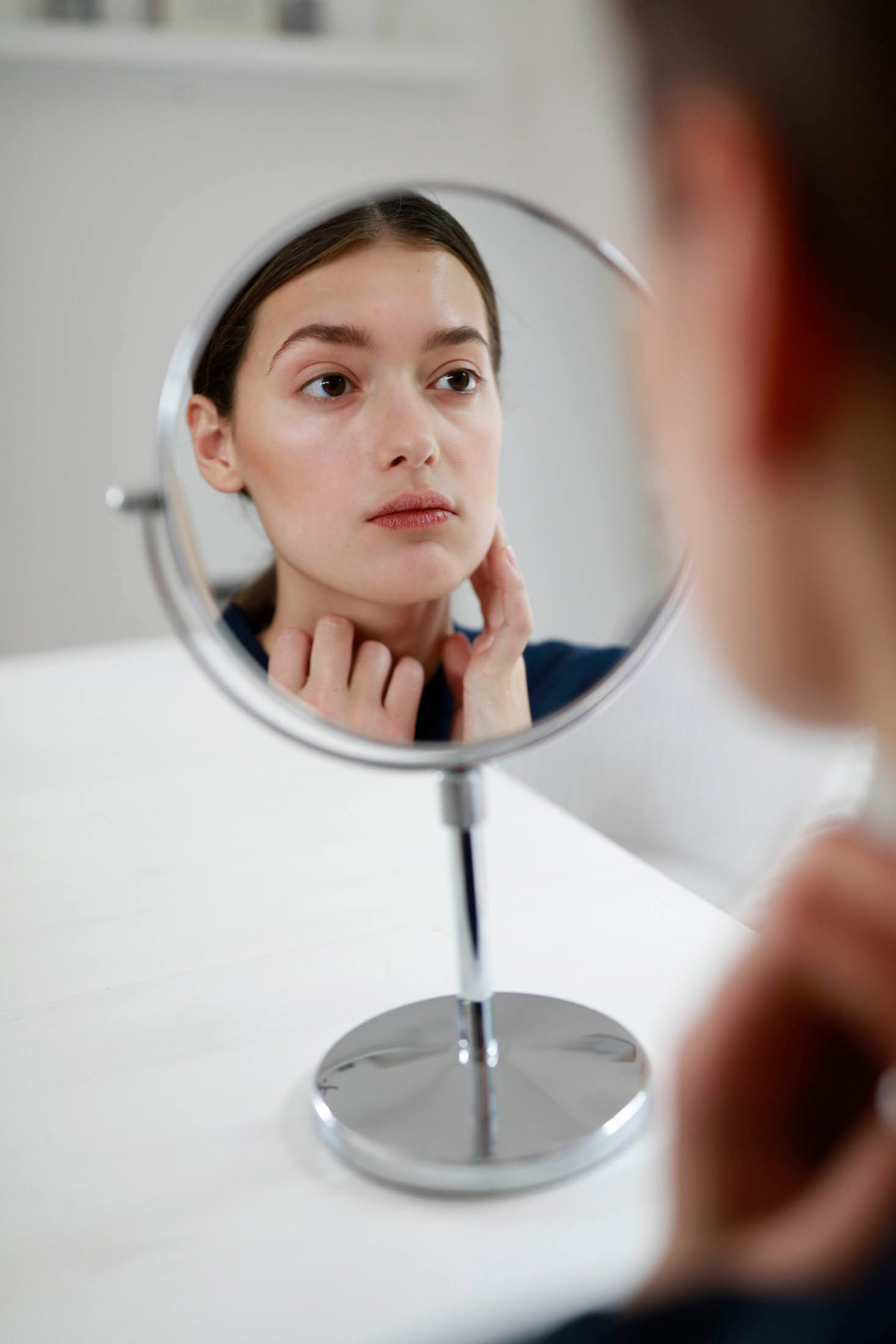 Eine junge Person schaut kritisch in den Spiegel.