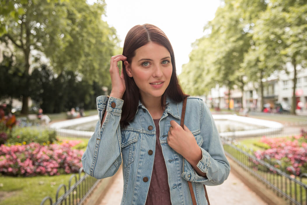 Eine junge Frau streicht ihr Haar nach hinten.