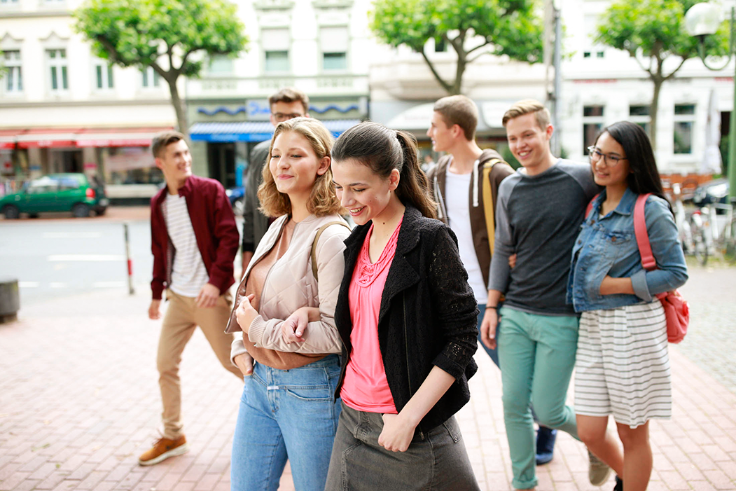 Das Bild zeigt eine Gruppe von Jugendlichen, die zusammen durch die Stadt geht.