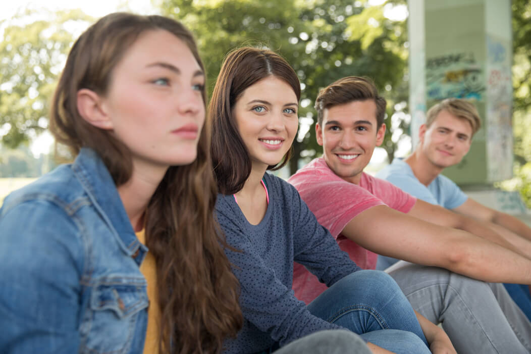 Eine Gruppe junger Menschen sitzt gemeinsam im Park.