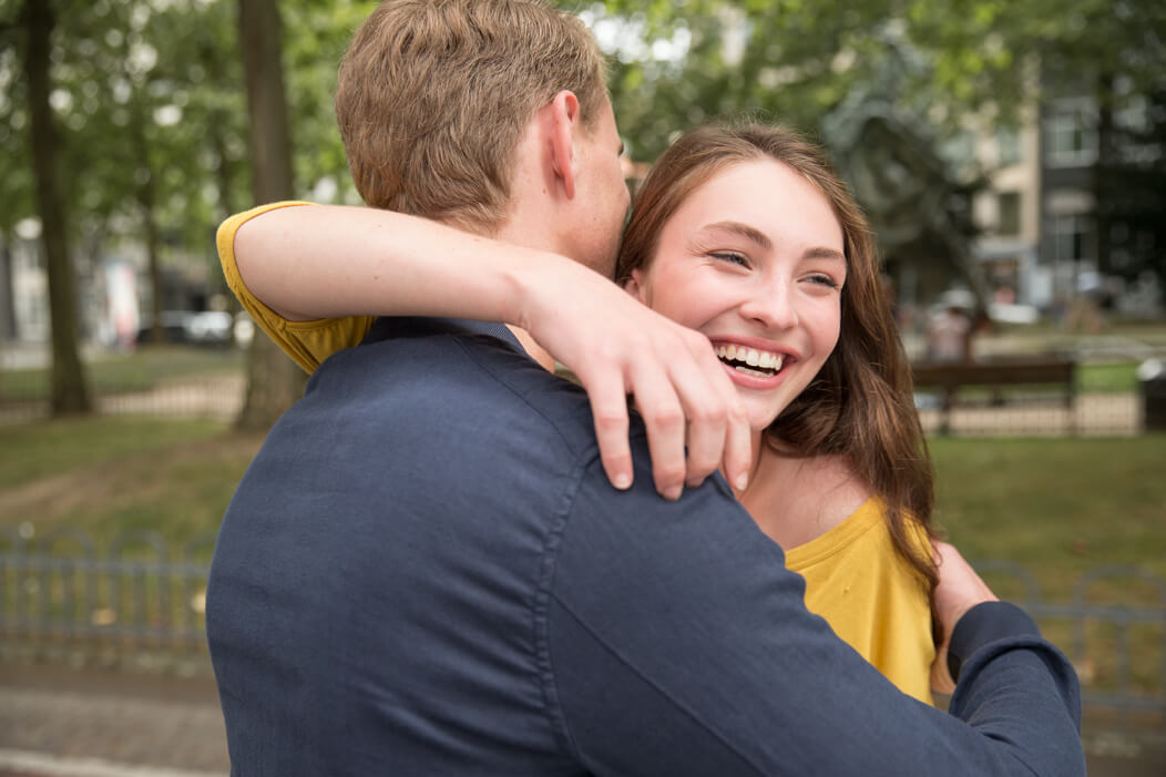 Junges, heterosexuelles Paar umarmt sich zur Begrüßung.