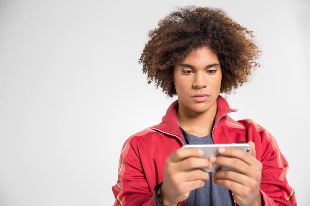 Junger Mann hält ein Smartphone in der Hand und informiert sich online.